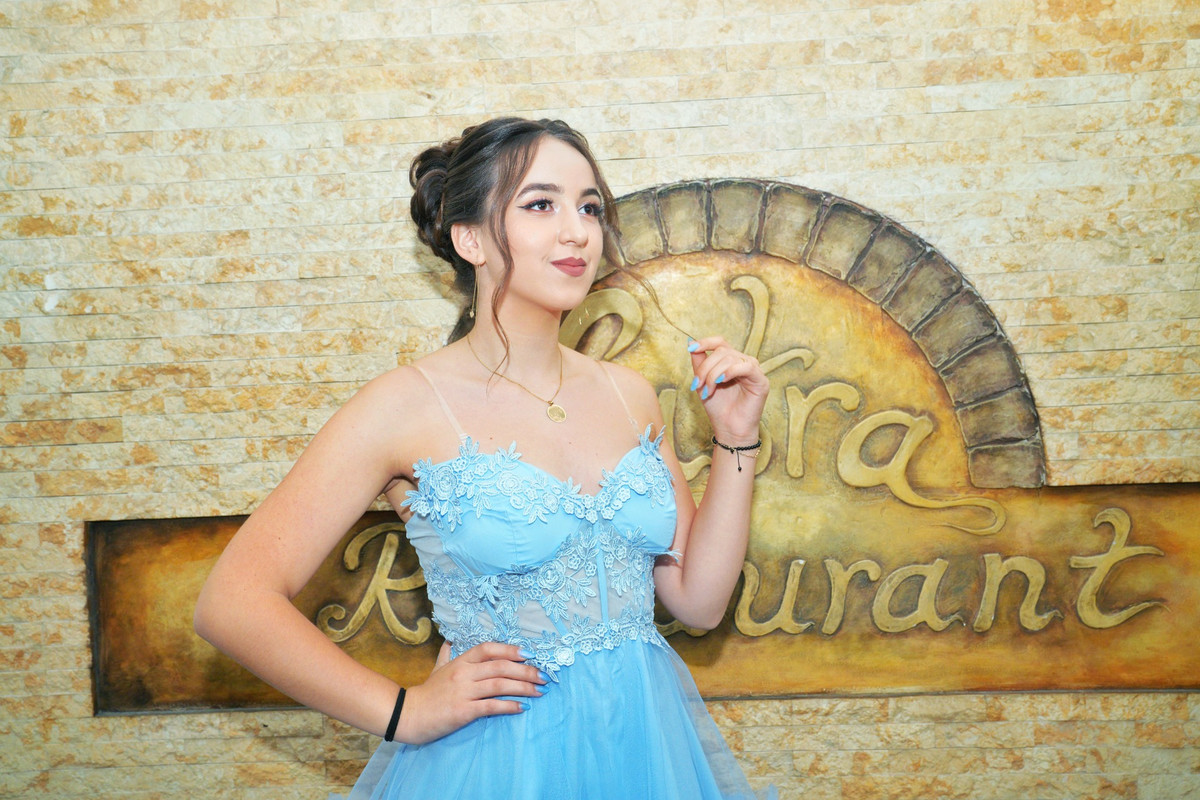 Sărbătorita în rochie bleu, în fața peretelui de piatră al restaurantului